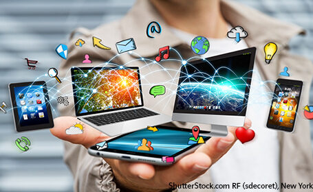 Symbole von Internet, Handy, Smartphone, Computer, Tablets schweben über einer Hand, die ein Smartphone hält