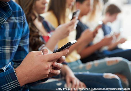 Schüler sitzen nebeneinander und schauen in ihr Handy