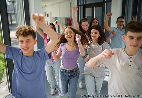 lachende und sich bewegende Schülerinnen und Schüler laufen durch eine Schule